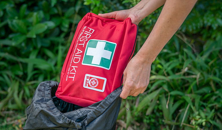 Person pulling a first aid kit out of a backpack. Photo: John Spencer/DPIE